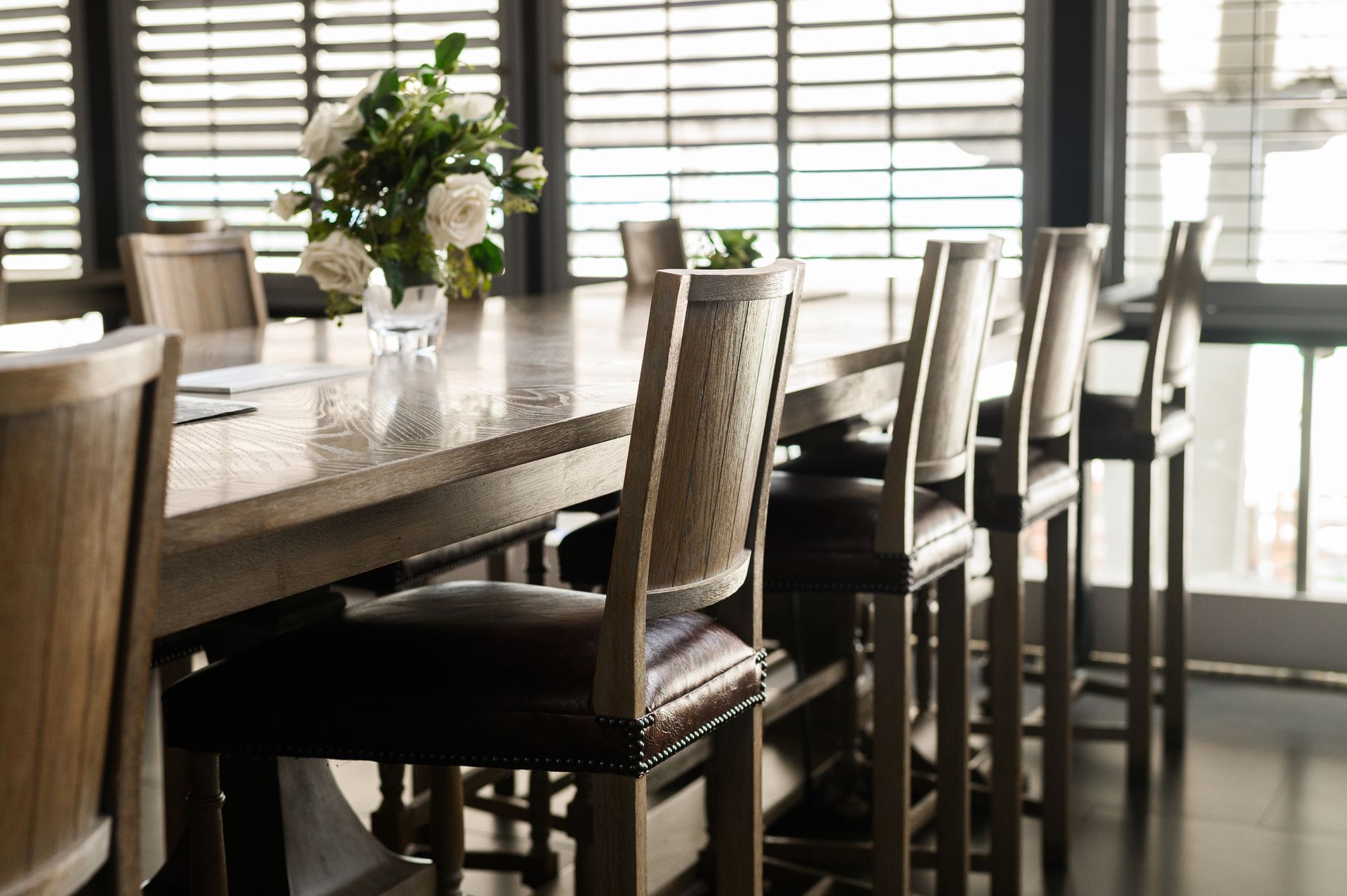 A well-designed country club restuarant with tables and chairs and shutters on the windows