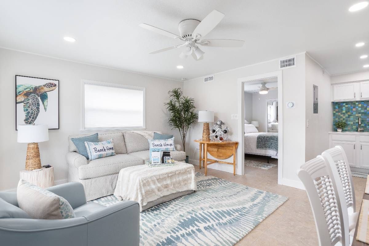 Bright white beach condo living room with wood and wicker furniture at Divine Interiors Group near Sarasota, FL
