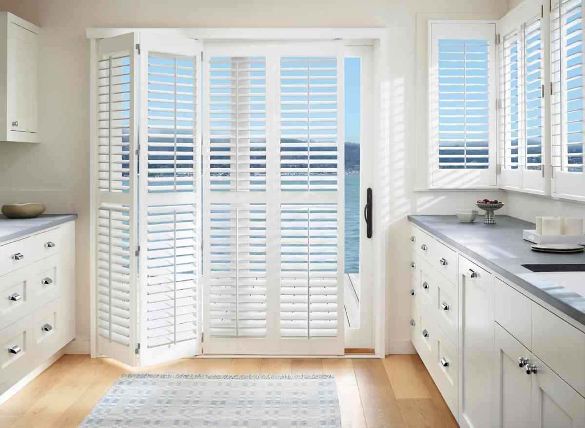 Palm Beach™ Polysatin™ Vinyl Shutters on a sliding door and windows in a bright white kitchenat Divine Interiors Group near Lakewood Ranch, Florida (FL)