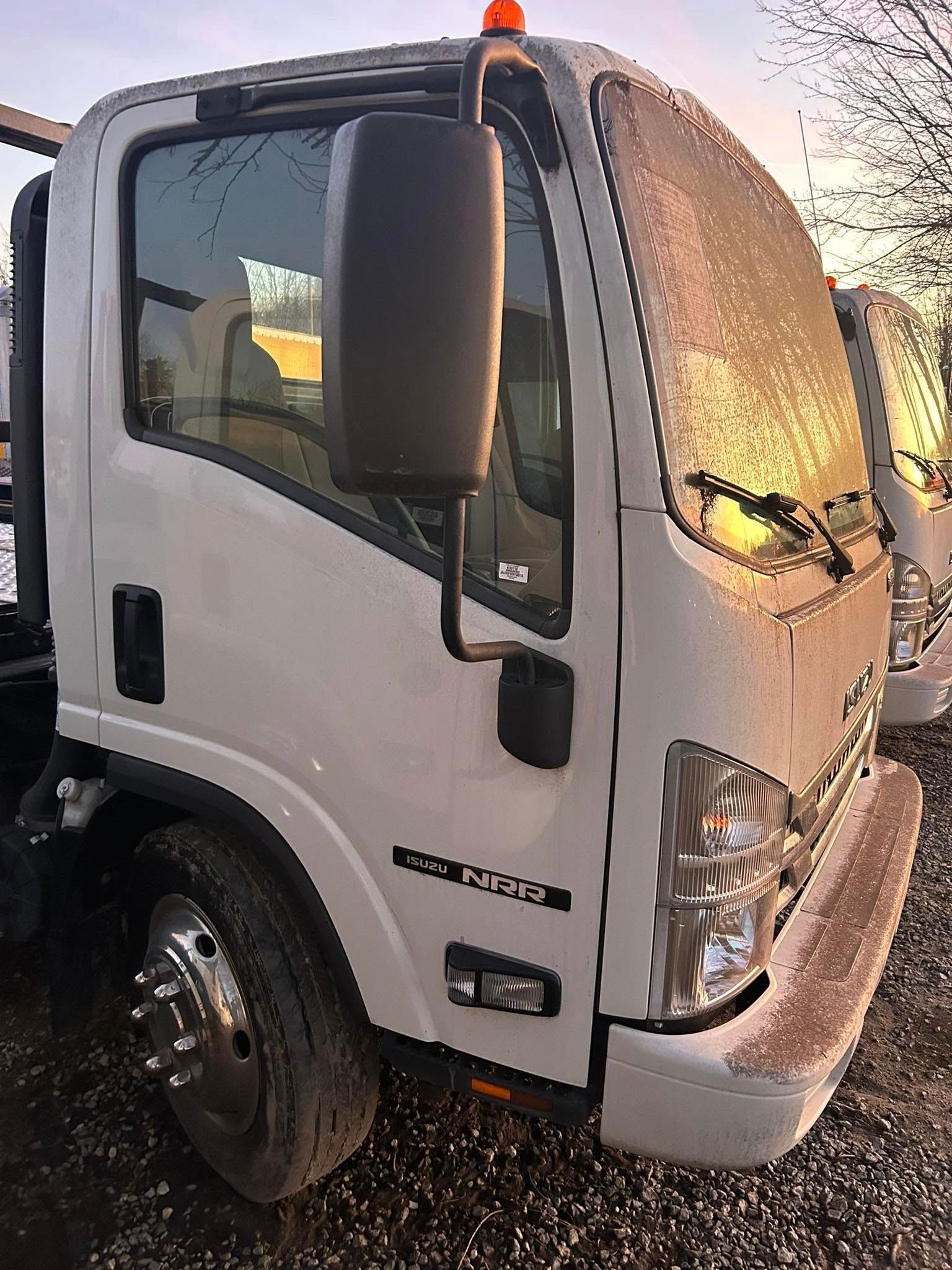 White commercial truck cab parked outdoors, covered in snow and ice at sunset.