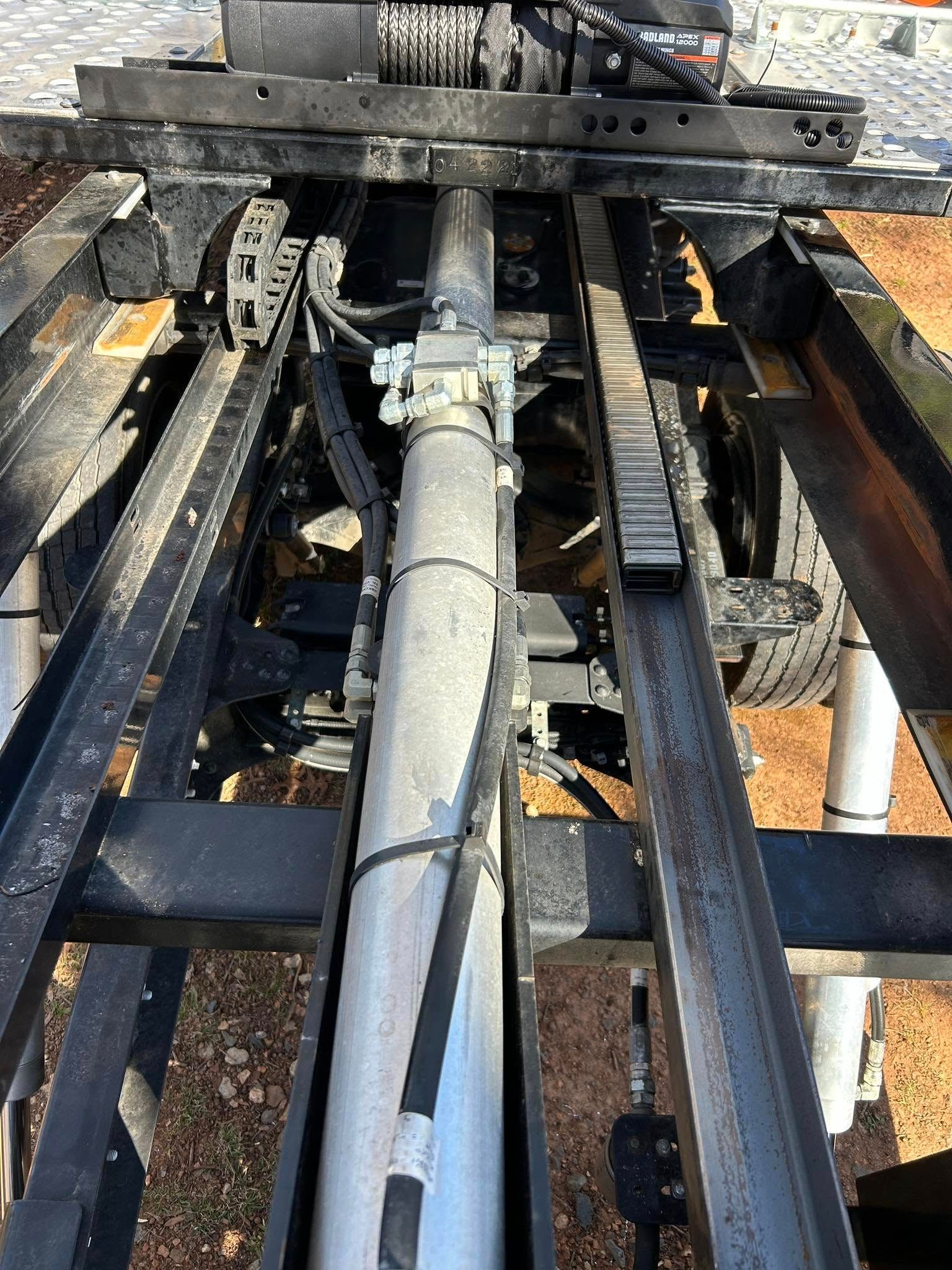 Industrial machinery with a central pipe running through metal rails and a dirty work platform above.