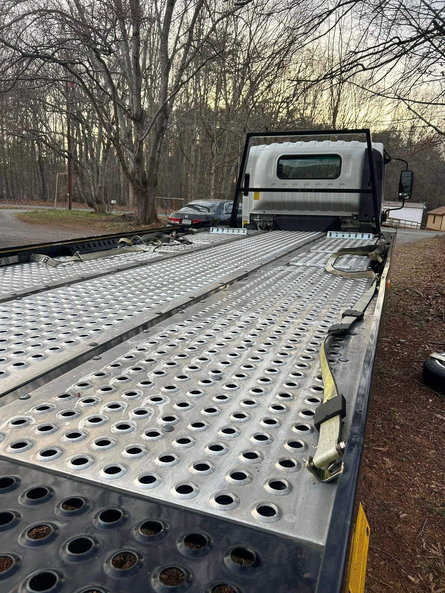 Truck hauling a perforated metal ramp through a wooded area