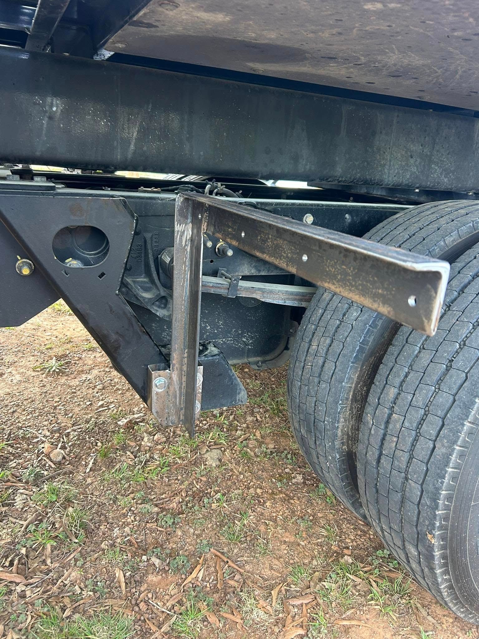 Close-up of a truck trailer’s undercarriage, with a metal support bracket beside the rear tires.