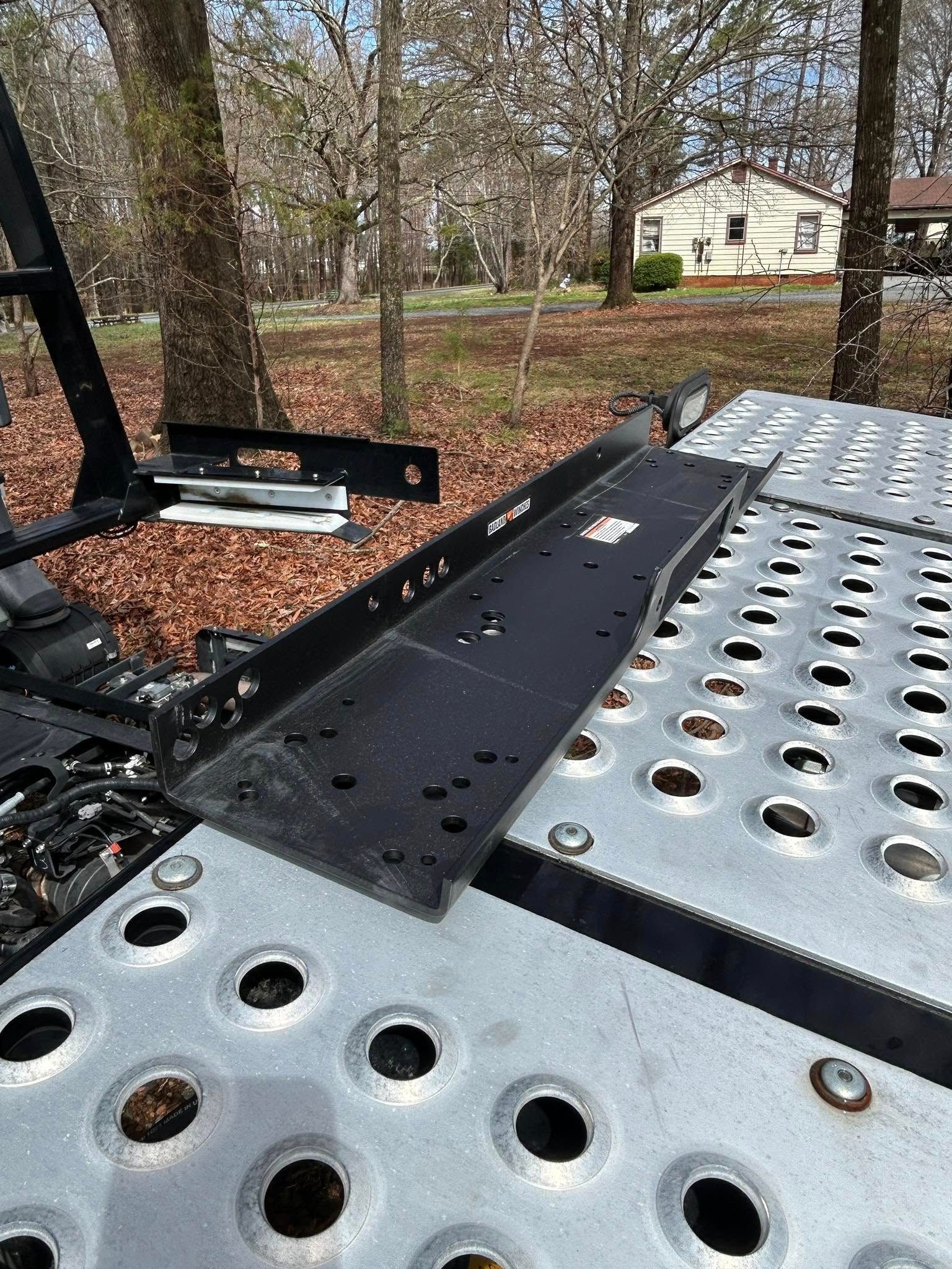 Metal equipment platform with perforated silver panels in a wooded yard near a small house.