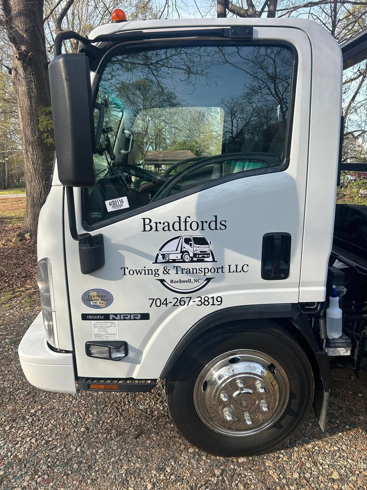 White Bradlords truck cab parked on gravel, side view with logo and phone number on door.