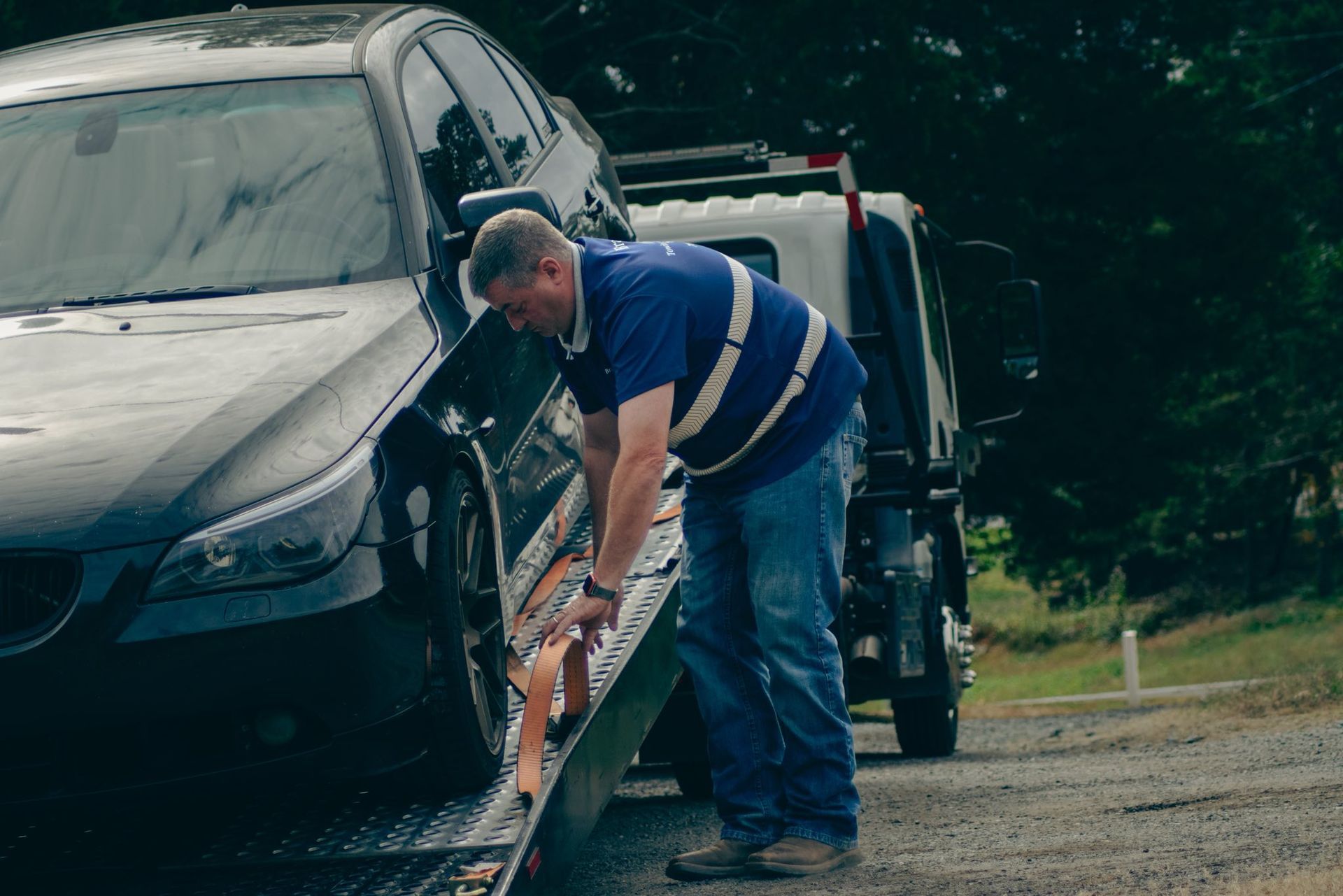 Man using a pressure washer to clean a black car in a driveway