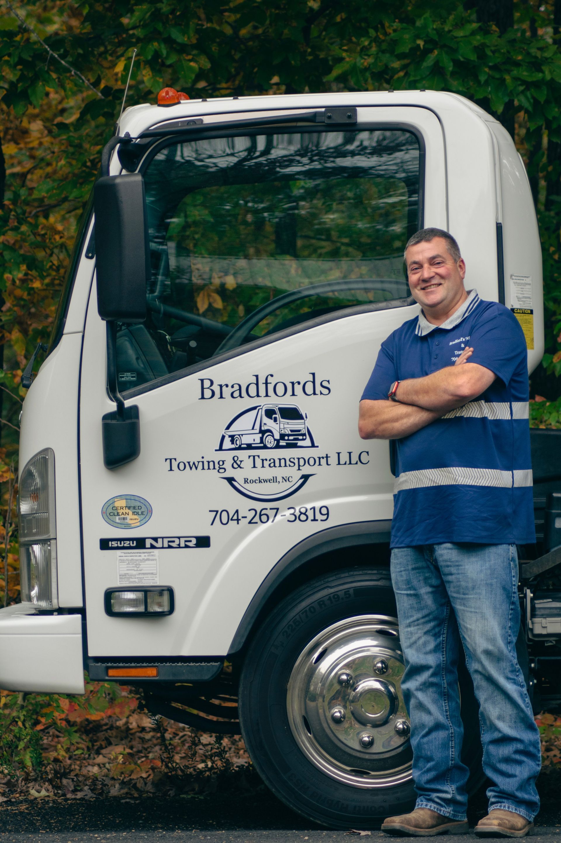 Man leaning on a Bradford’s Towing & Transport truck, smiling beside the cab.