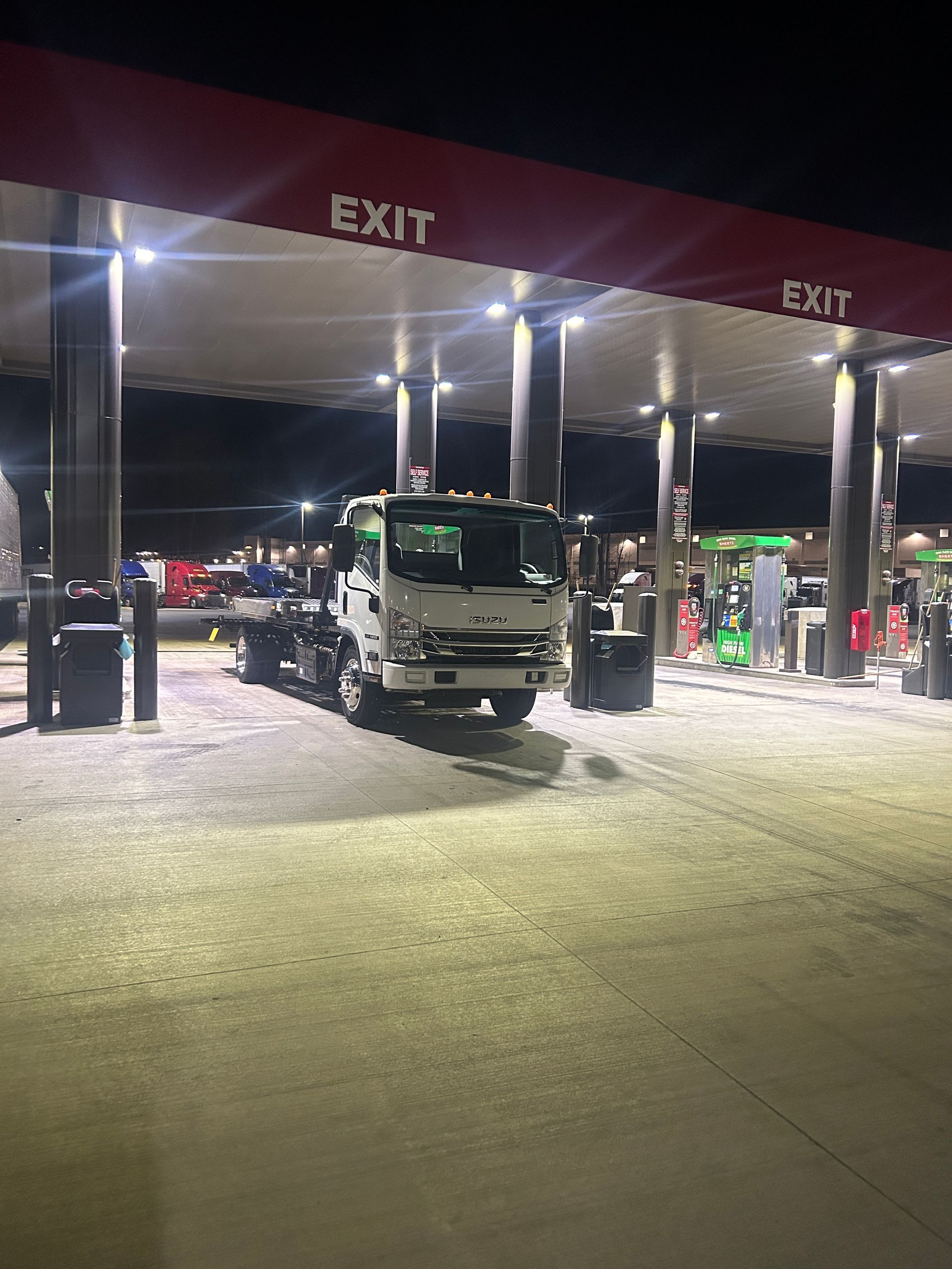 Truck at a lit gas station under exit signs at night