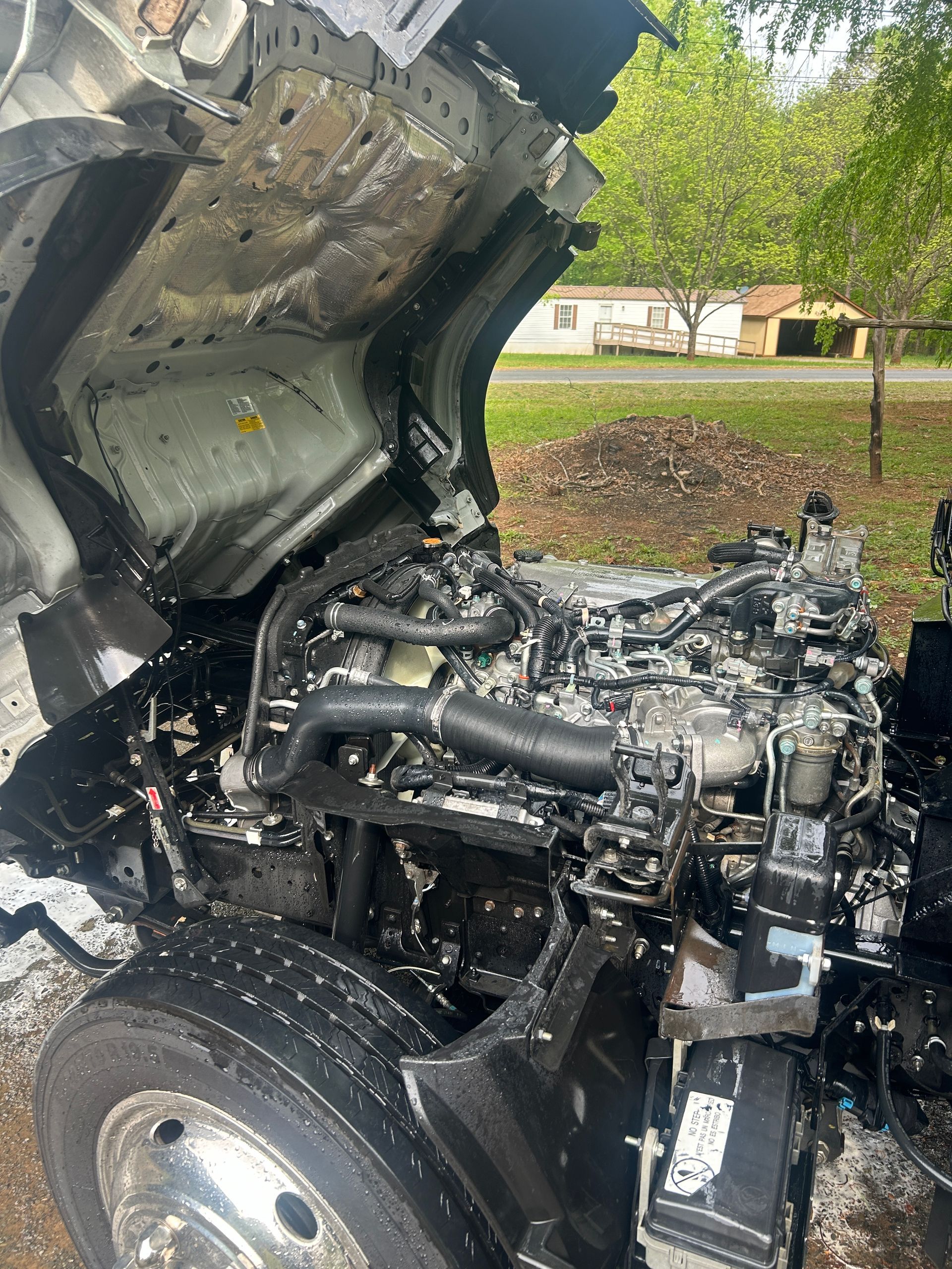 Truck with hood open, showing a damaged engine and charred components after a fire.