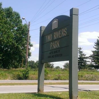 Milo Rivers Park entrance sign beside a roadside with trees and blue sky