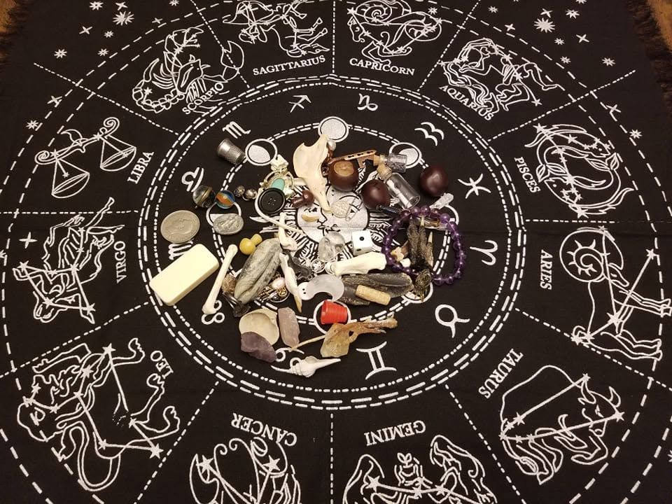 Assorted pills and capsules scattered on a black zodiac cloth with white astrological symbols