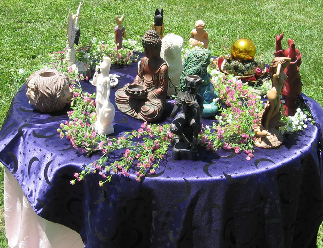 Miniature figurines arranged on a purple cloth-covered table, decorated with flowers and candles.