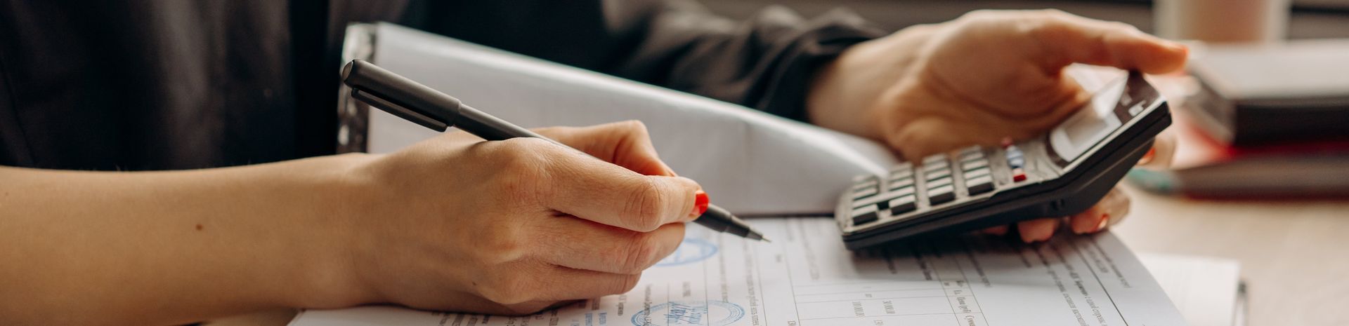 A person is using a calculator and writing on a piece of paper.