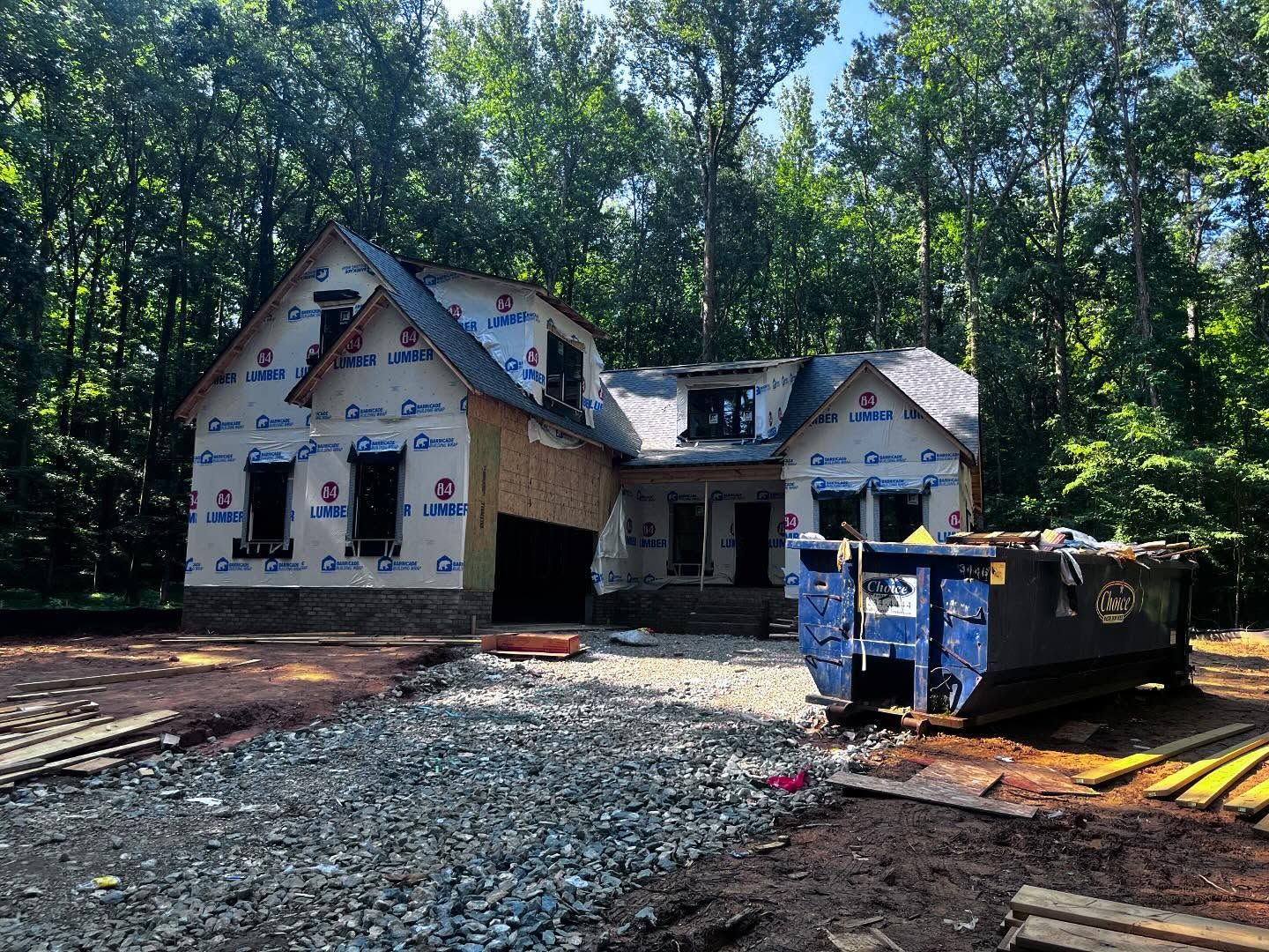 New house under construction with blue dumpster in front.
