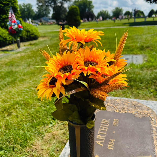 Pink roses and lilies in a flower arrangement in front of a dark memorial stone