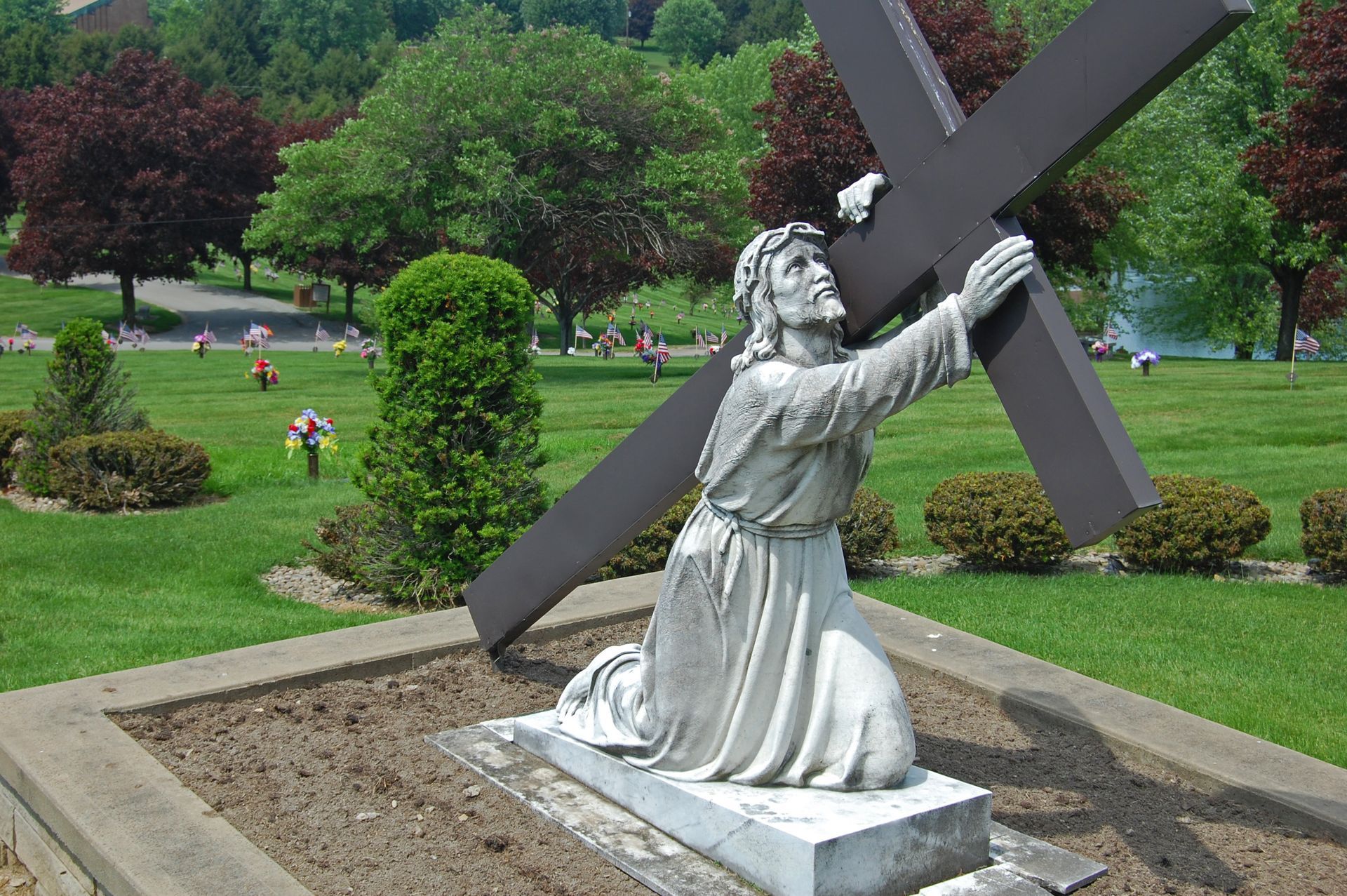 beautiful photo of a large stone statue of Christ carrying the cross in the chapel garden