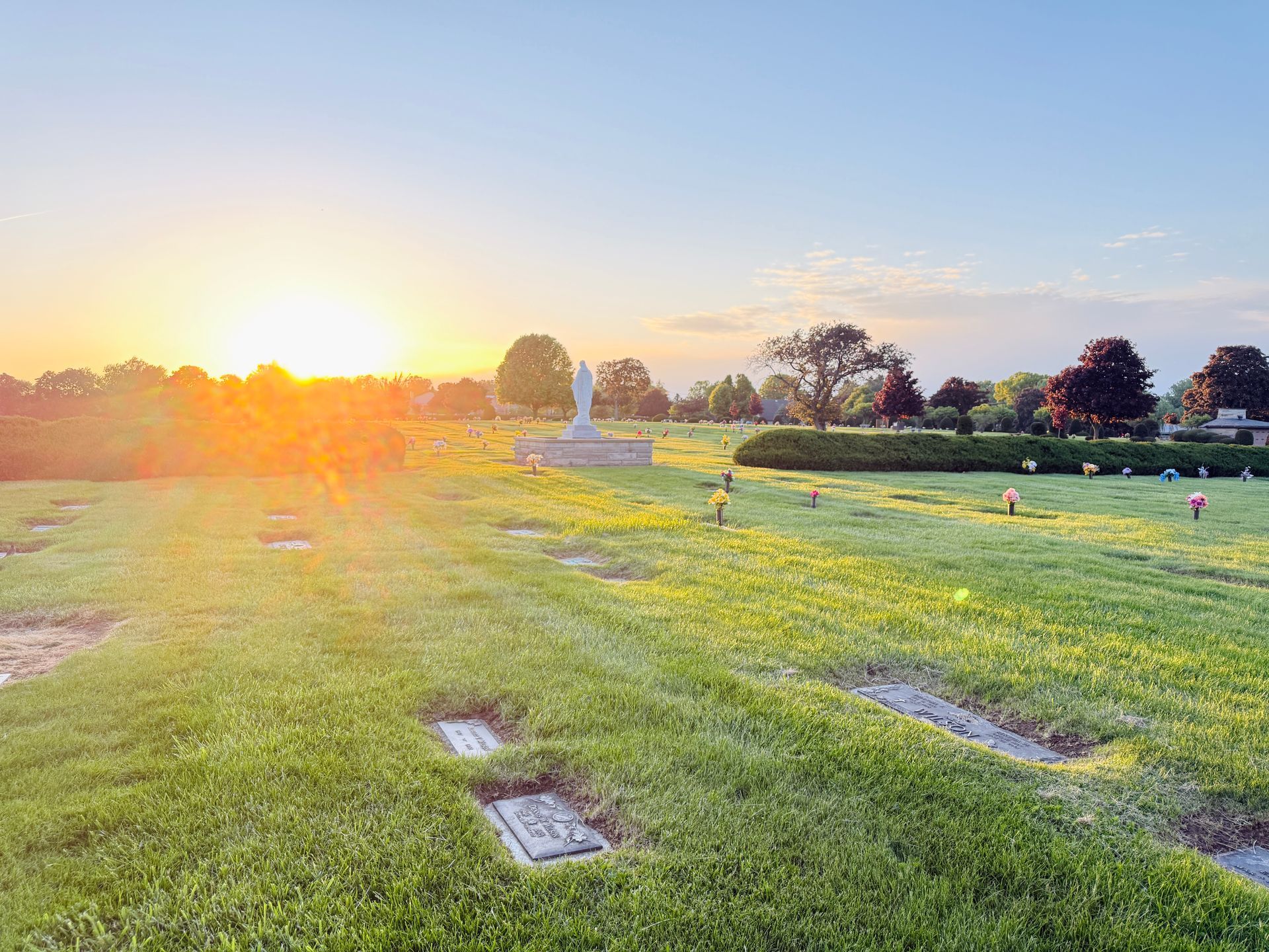 Sunlit cemetery lawn with rows of graves and headstones at sunset