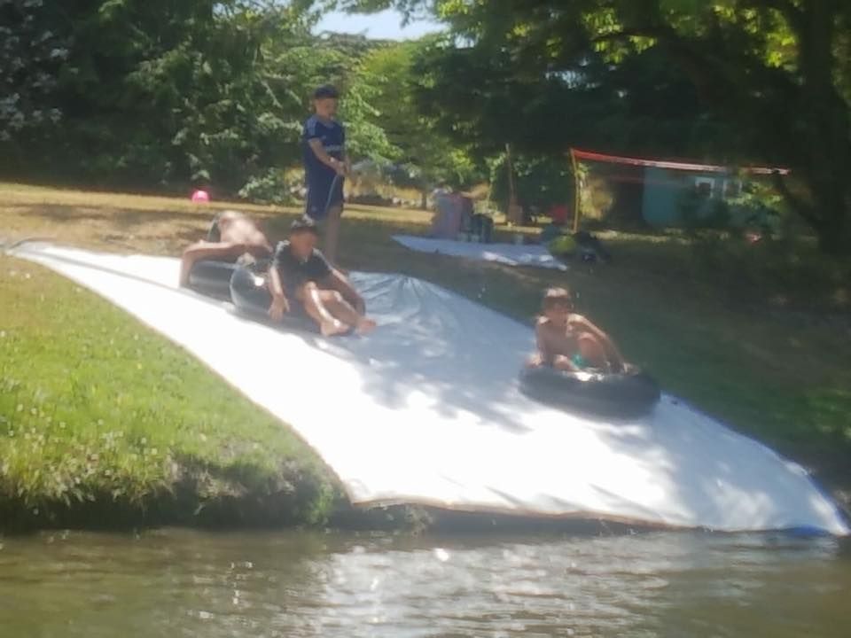 A group of children are playing on a water slide.