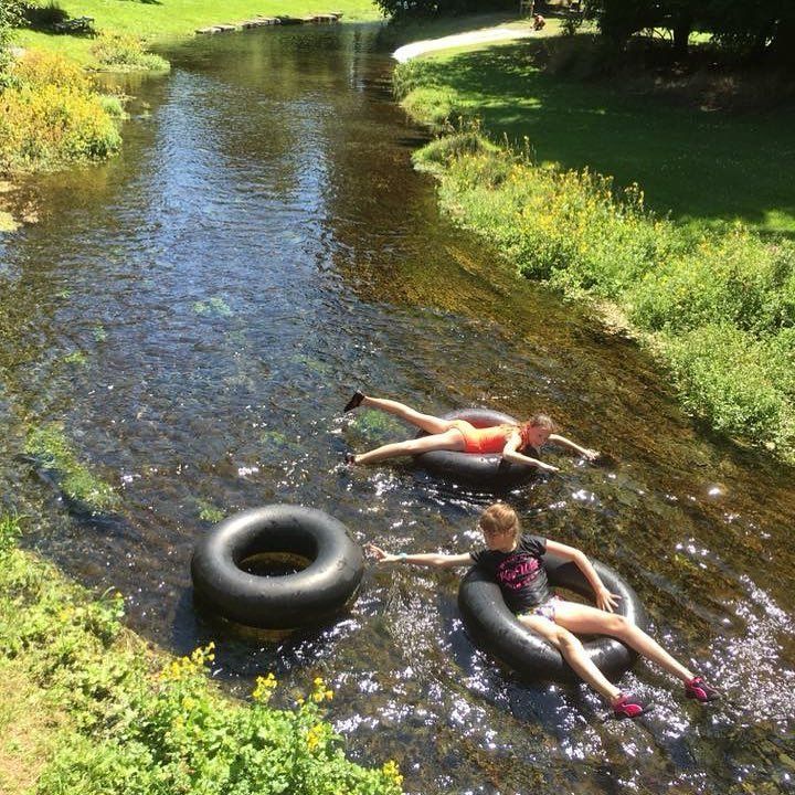 Two people are floating down a river in inner tubes.