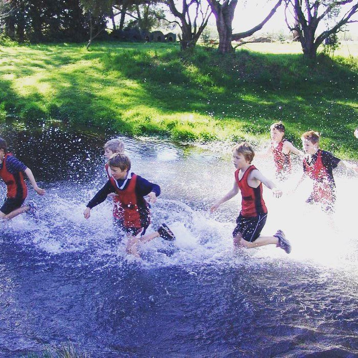 A group of young boys are running through a stream