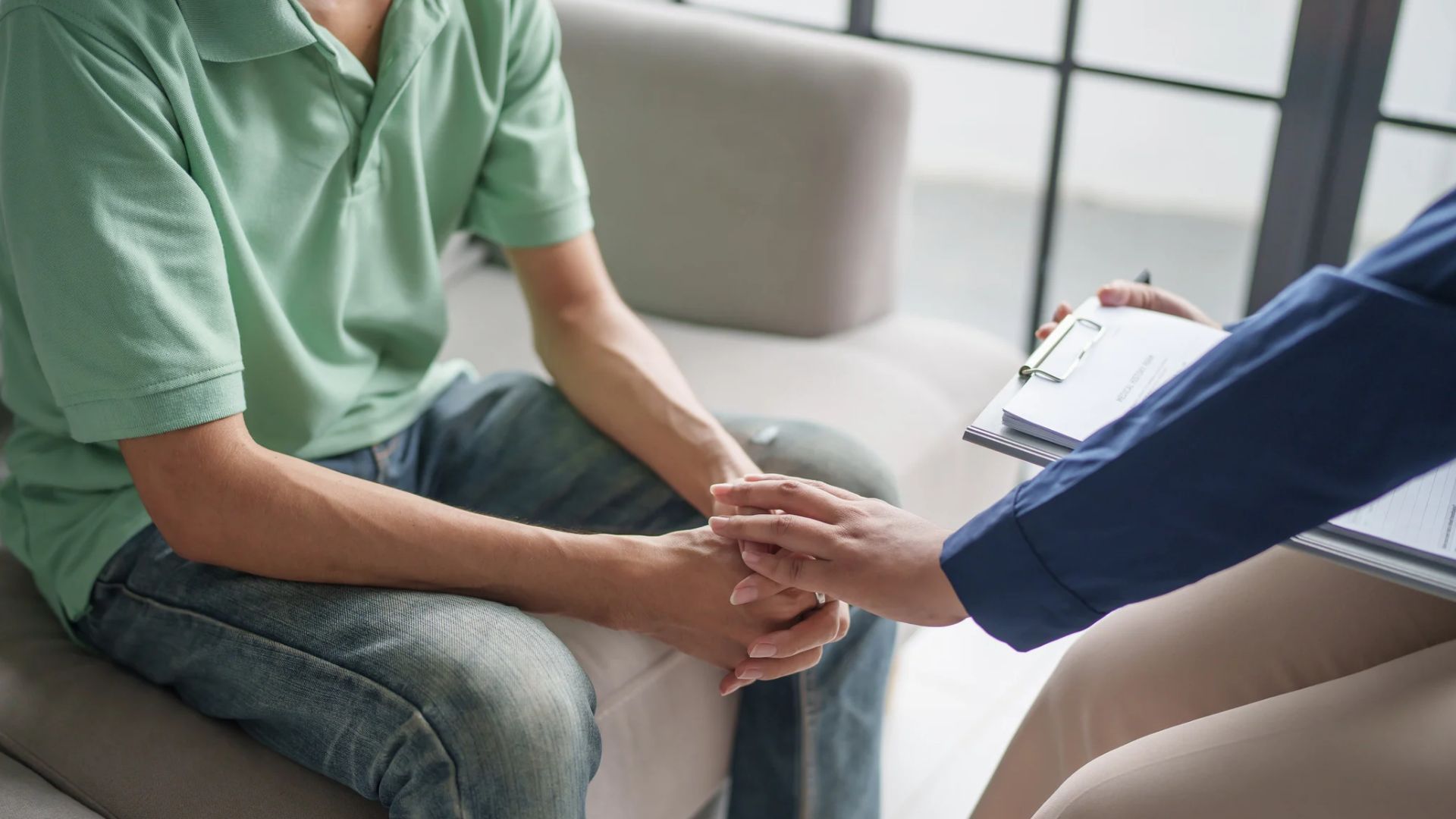 Person holding hands with a counselor in a therapy office during a supportive conversation