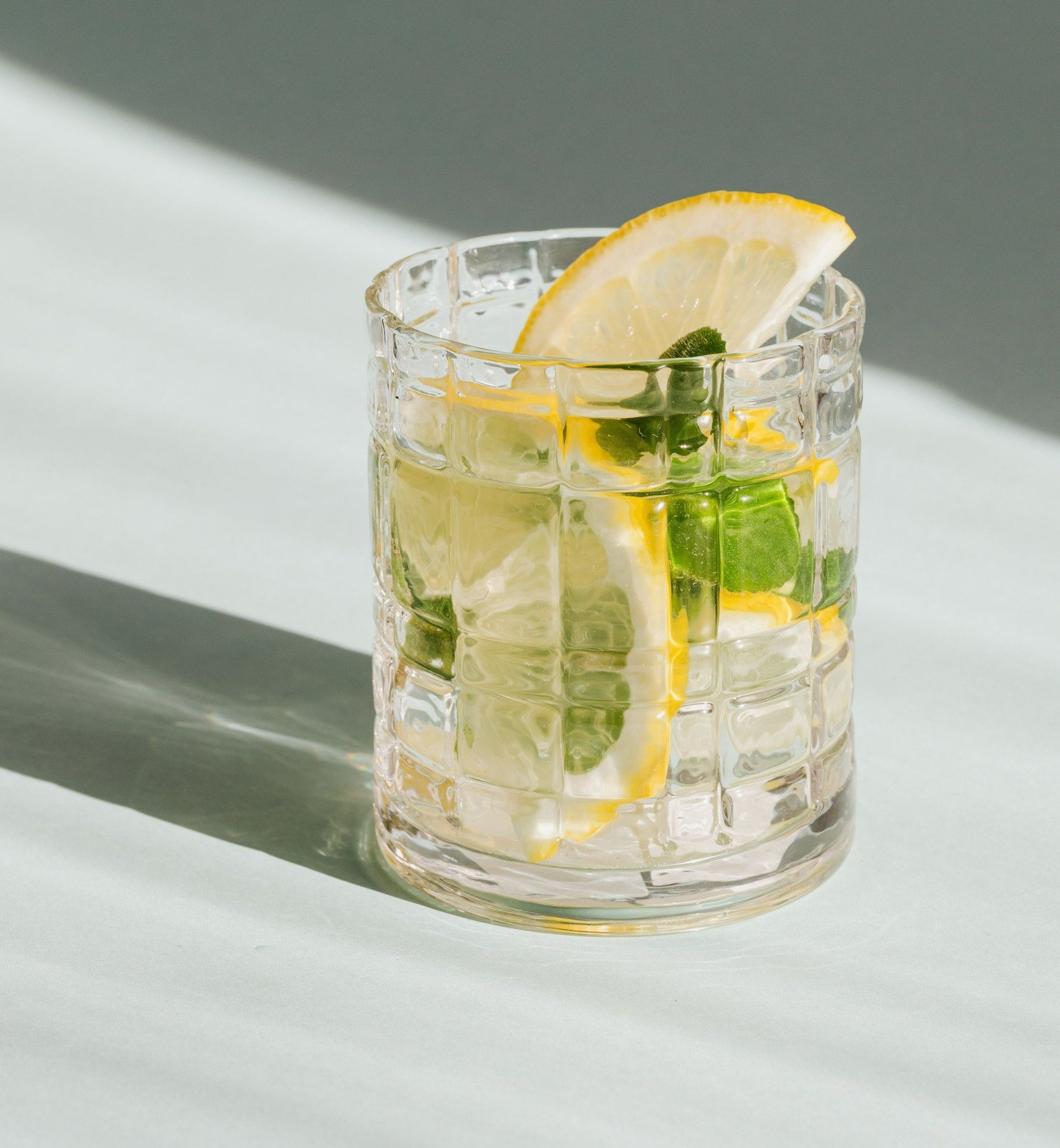 A craft Mojito cocktail served with lime slices and mint leaves on a table.