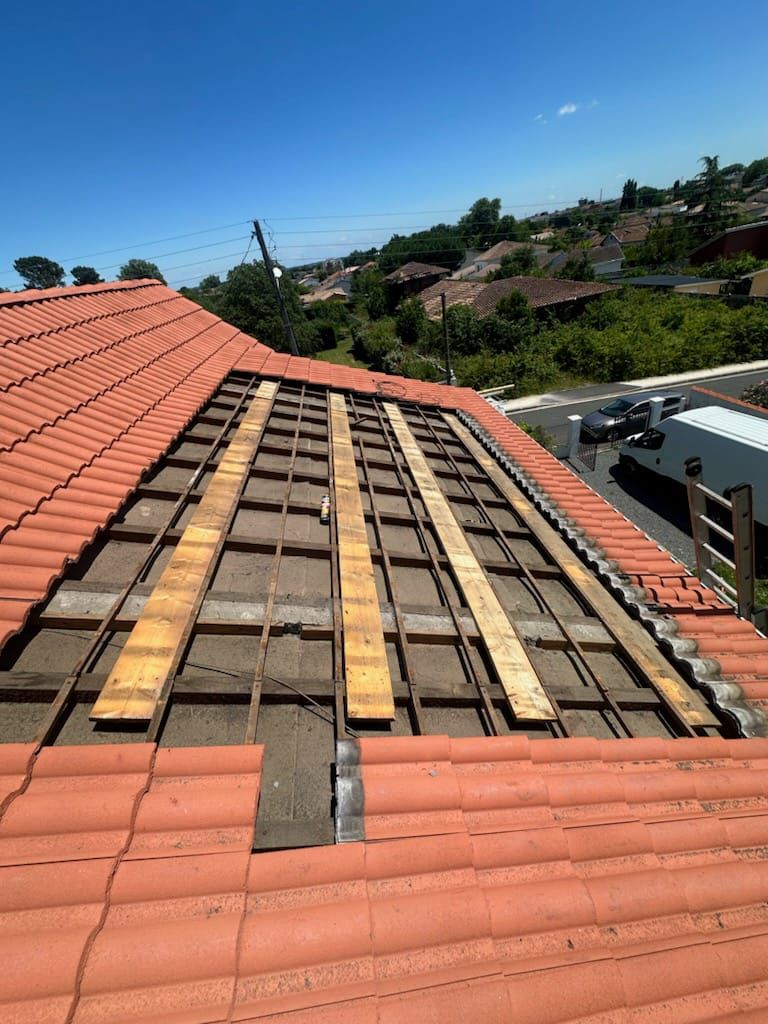 Le toit d'une maison est en train d'être réparé avec des poutres en bois.