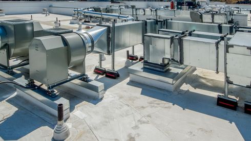 A rooftop with a lot of ventilation pipes and fans on it.