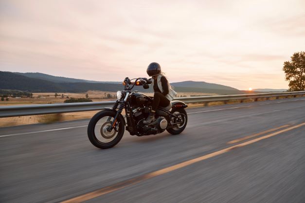 A person is riding a motorcycle down a road at sunset.