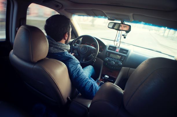 A man is sitting in the driver 's seat of a car.