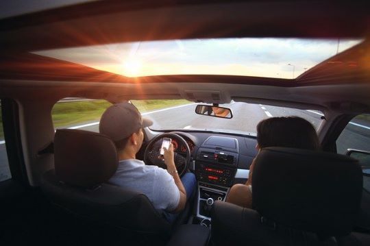 A man is driving a car and looking at his phone.