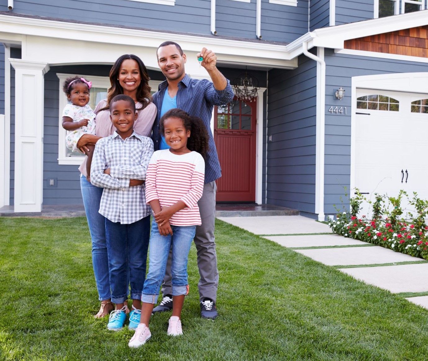 A family is standing in front of their new house holding the keys.
