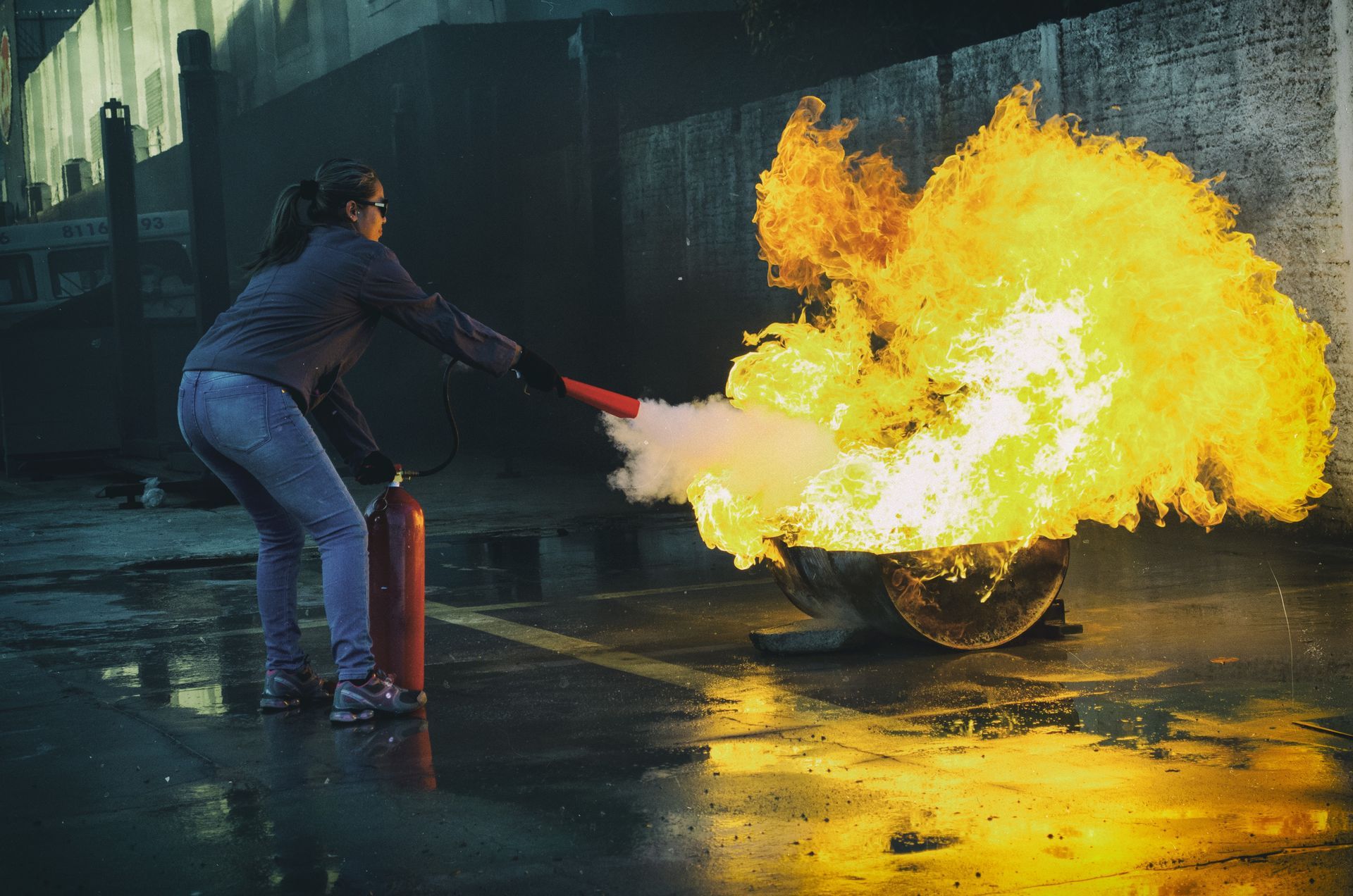 A woman is using a fire extinguisher to put out a fire.