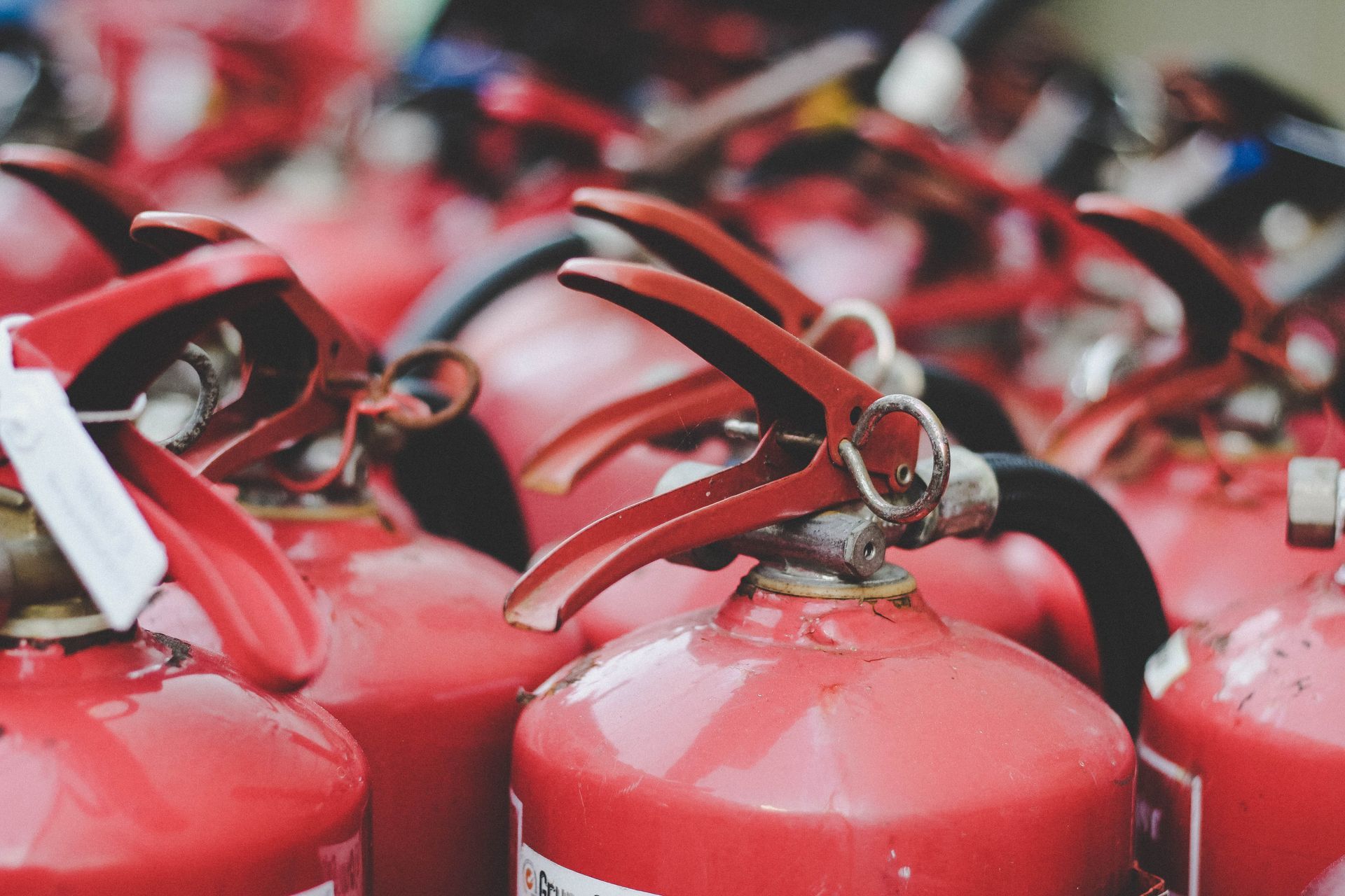 A bunch of red fire extinguishers are stacked on top of each other.