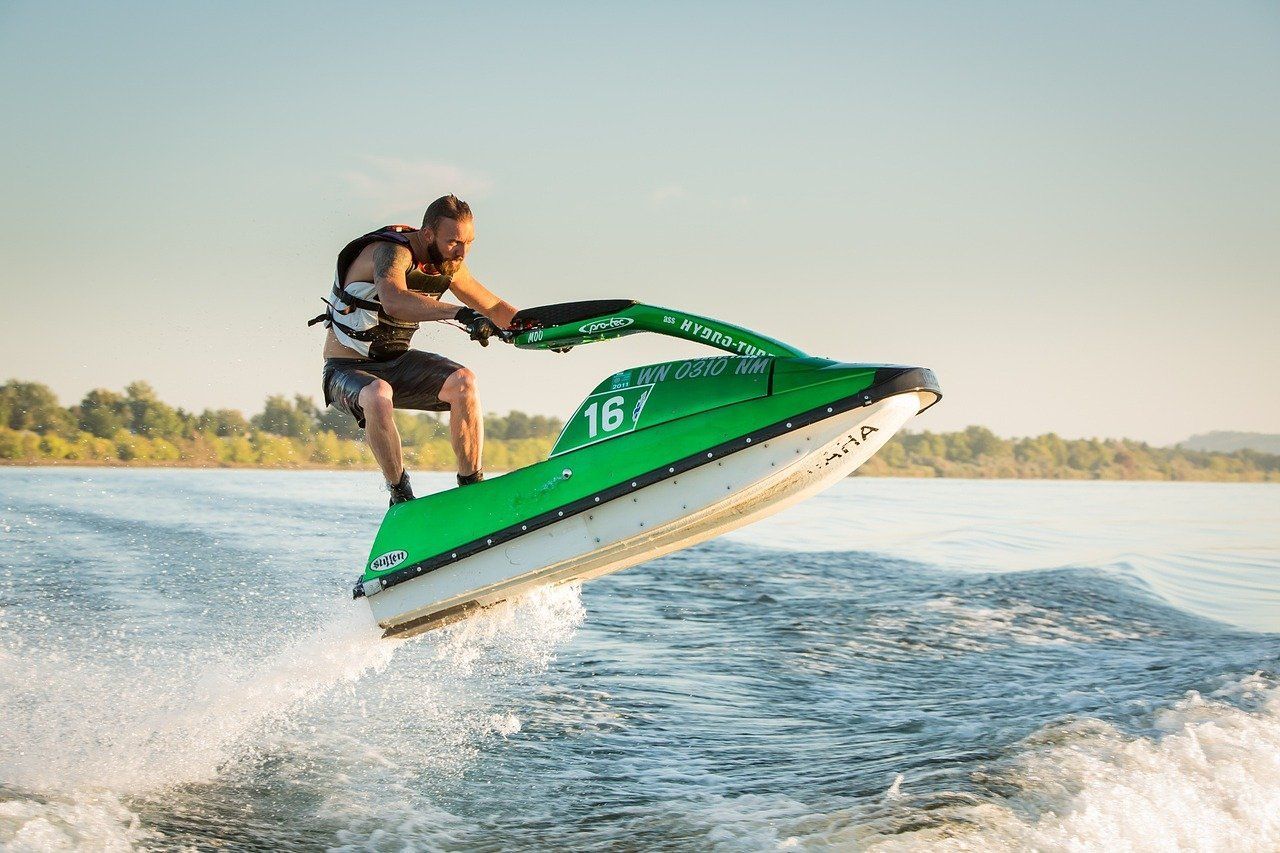 A man is riding a green jet ski on a lake.