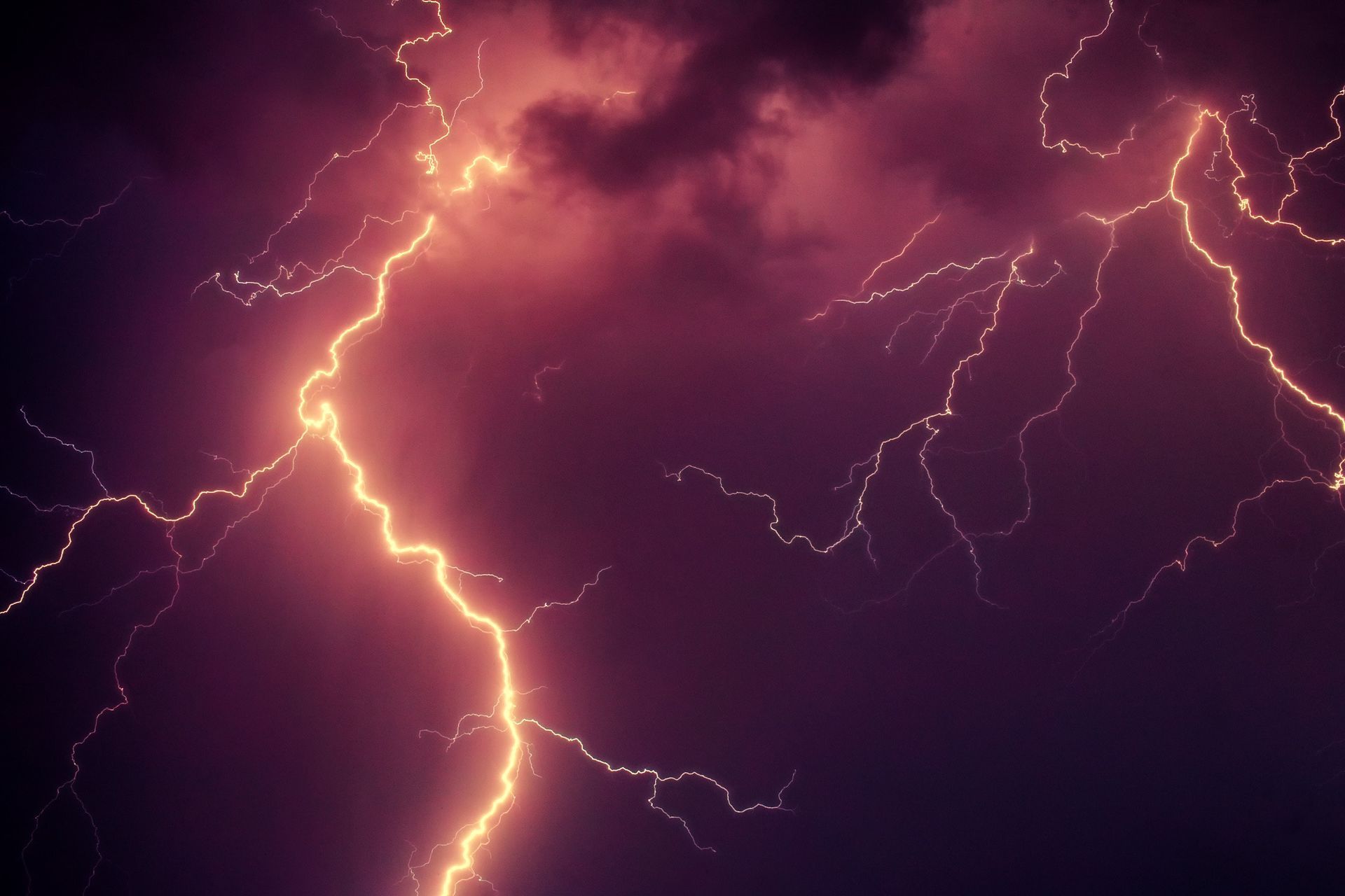 A purple sky with a lot of lightning strikes