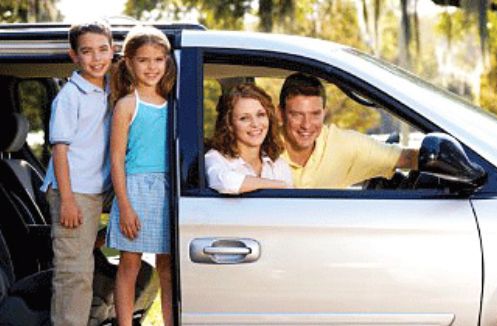 A family is sitting in a car with the door open.