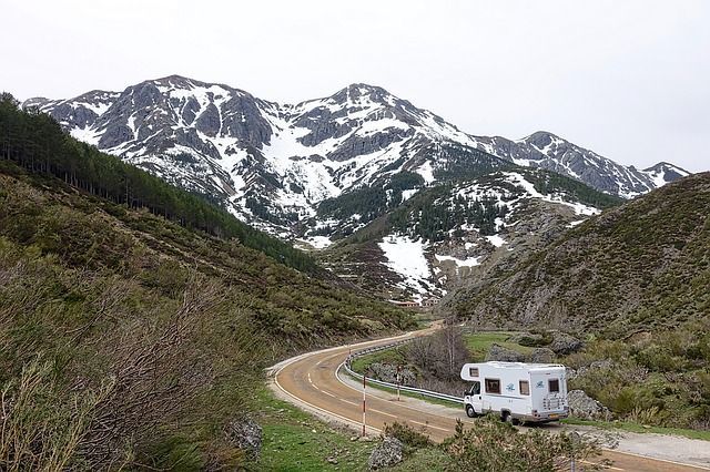 A rv is driving down a dirt road in the mountains.