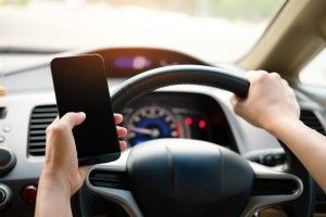 A person is holding a cell phone while driving a car.