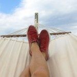 A person is laying in a hammock with their feet up.