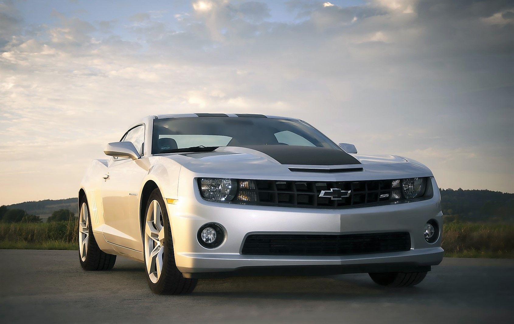 A silver chevrolet camaro is parked on the side of the road