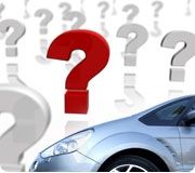 A silver car is parked in front of a bunch of question marks.