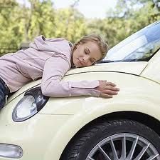 A woman is laying on the hood of a car.