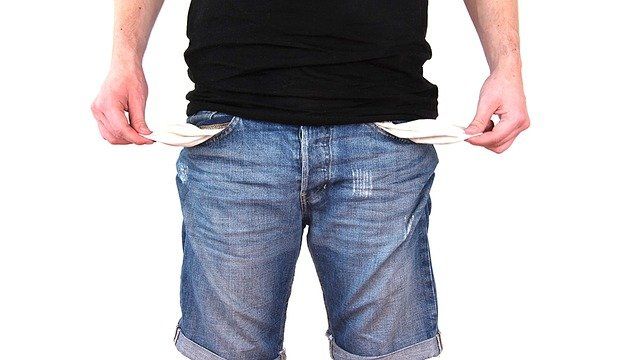 A man in a black shirt and blue shorts has his pockets empty