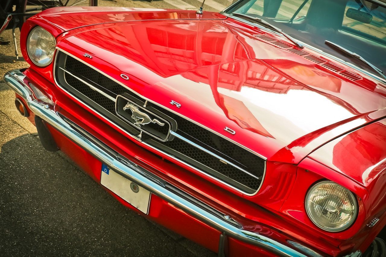 A red ford mustang is parked on the side of the road.