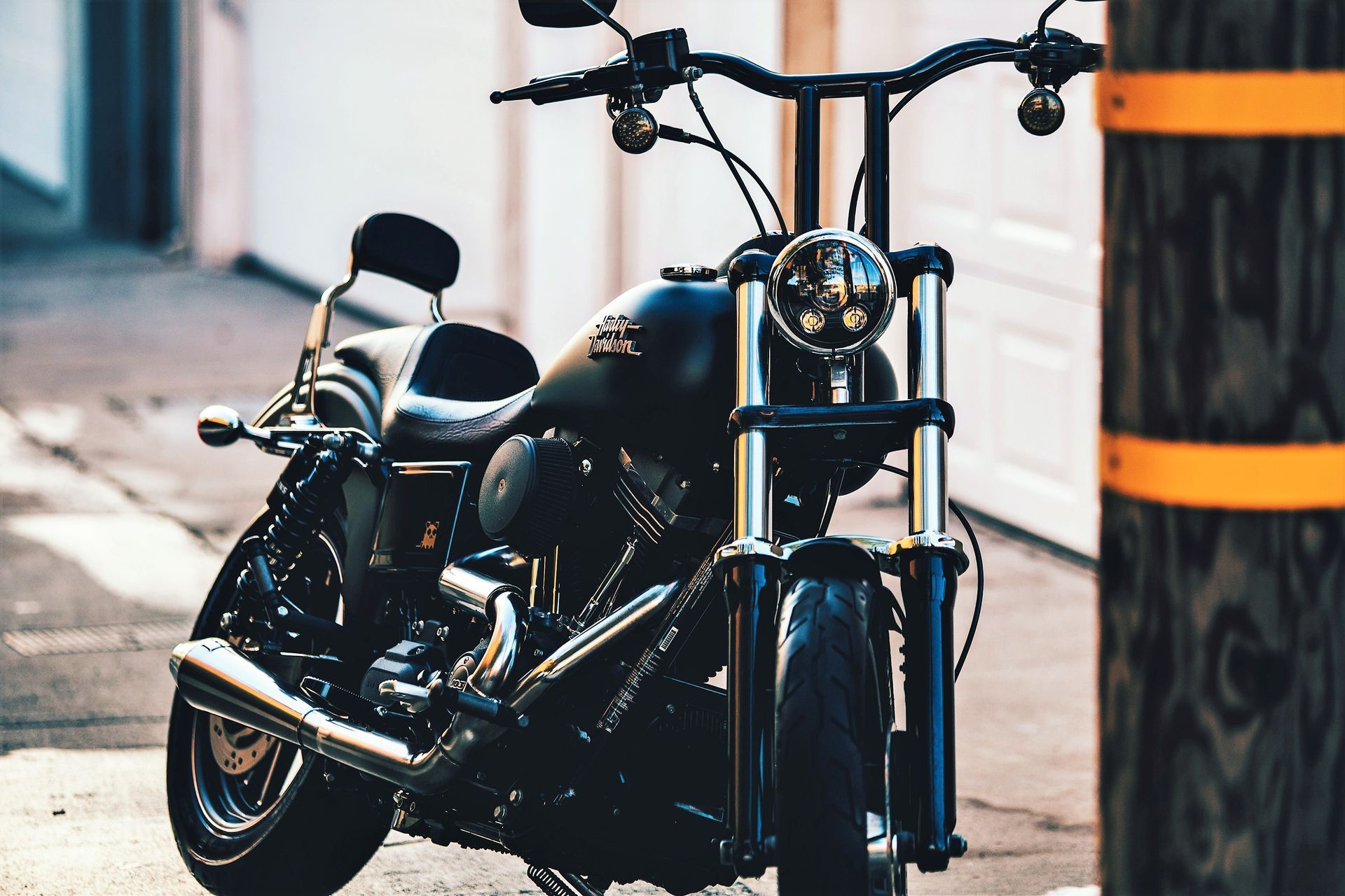 A black motorcycle is parked on the side of the road next to a wooden pole.