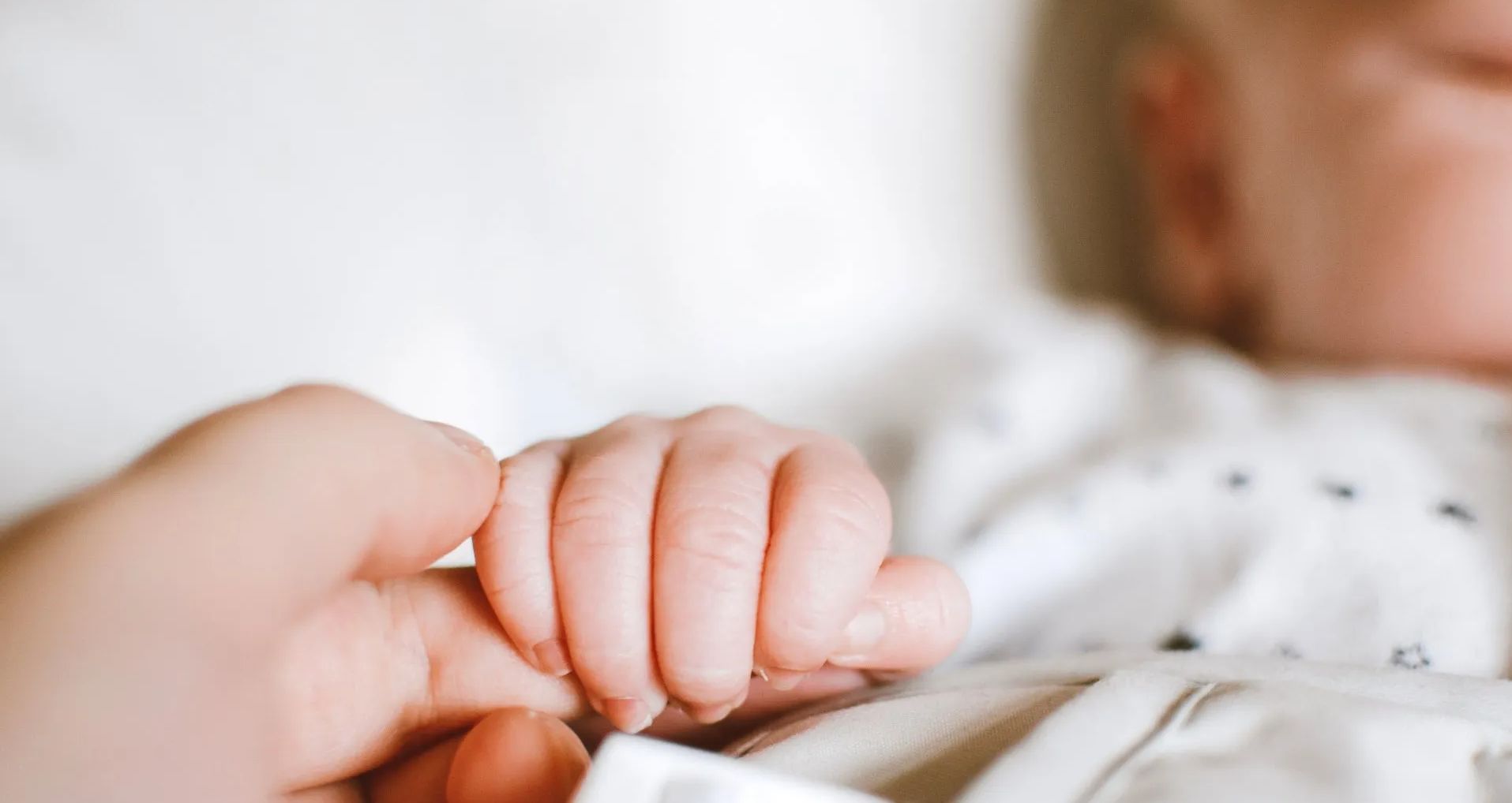 A close up of a person holding a baby 's hand.