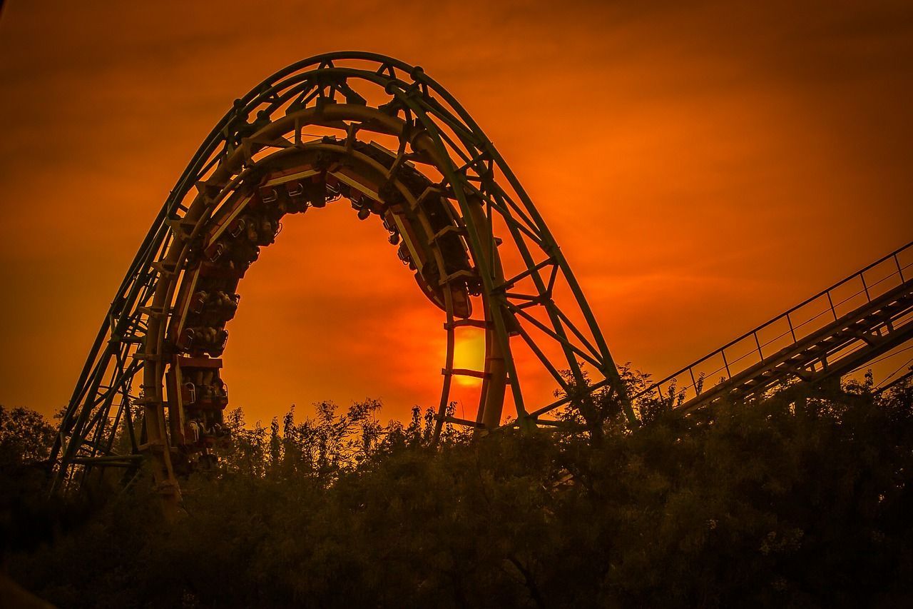 A roller coaster is going down a hill at sunset.