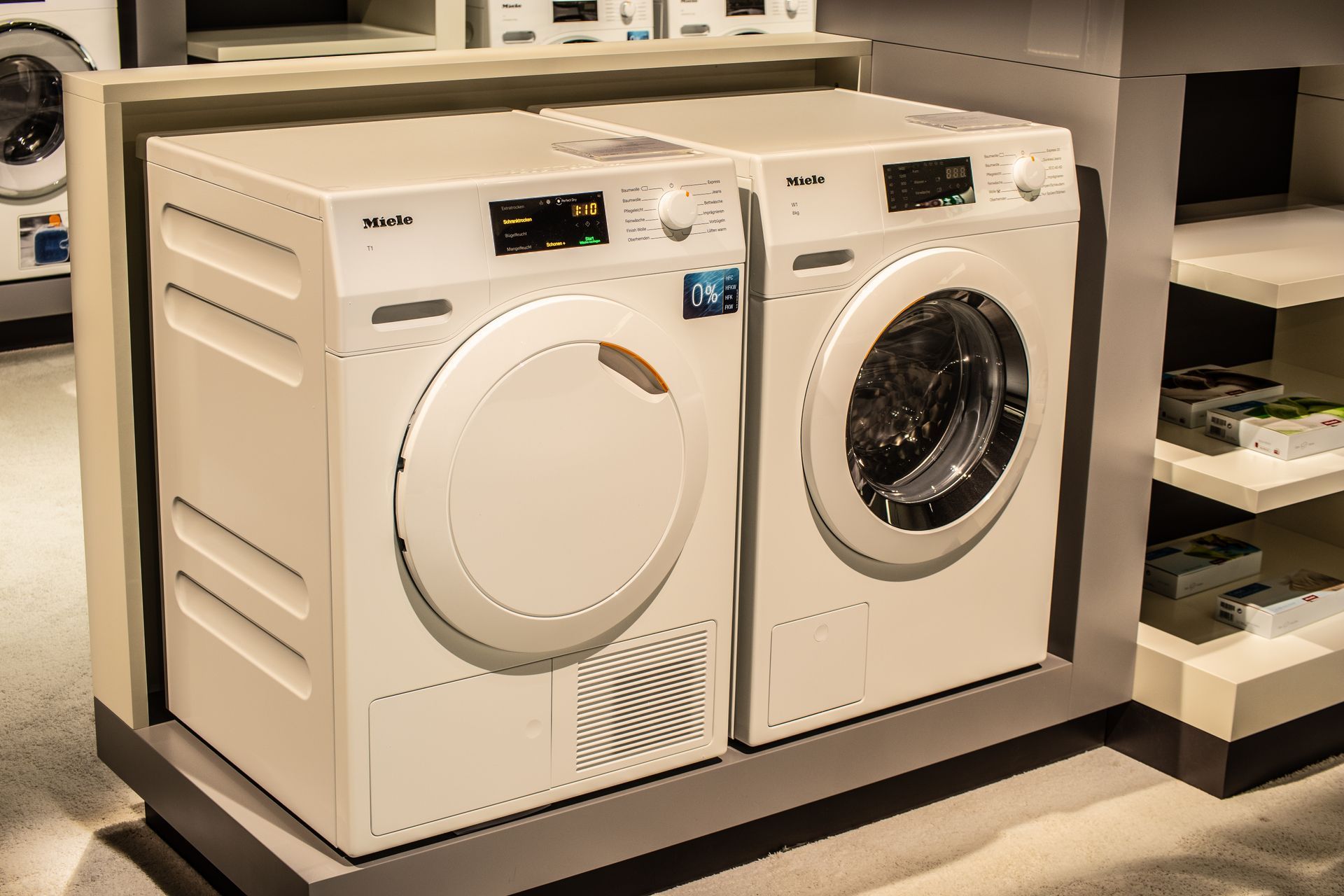 Two white front-loading laundry machines displayed on a store showroom floor