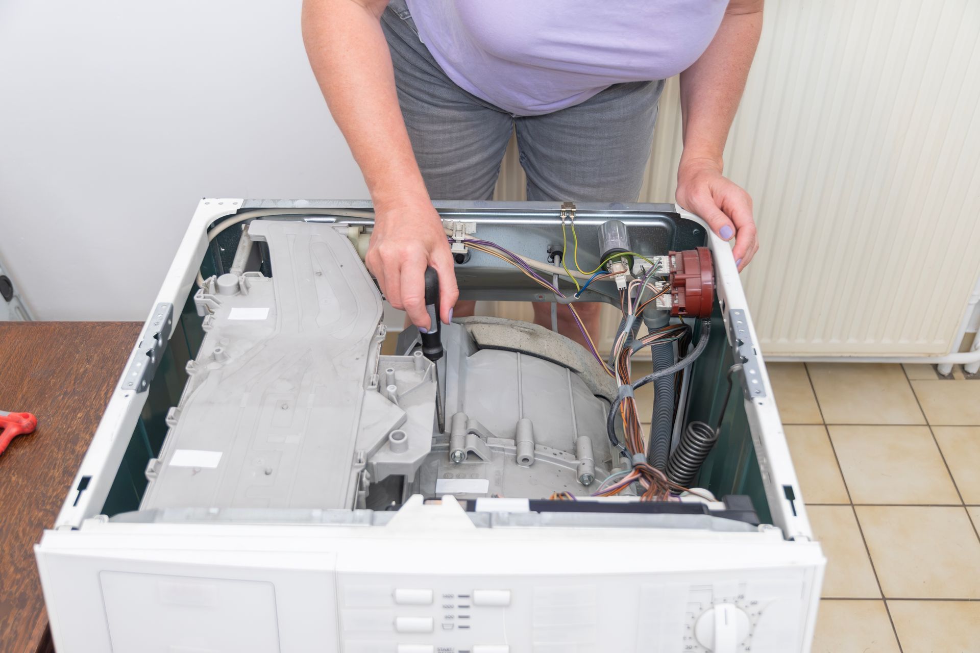 Person working inside an open top-load washing machine during repair